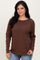 woman wearing a brown long sleeve top with a rounded neckline and relaxed fit, paired with light blue jeans