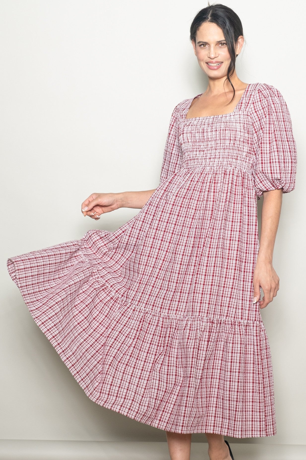woman wearing a red and white checked puff sleeve midi dress with a smocked bodice and tiered hem