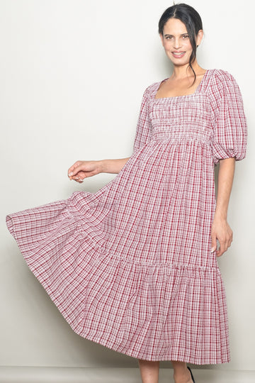 woman wearing a red and white checked puff sleeve midi dress with a smocked bodice and tiered hem