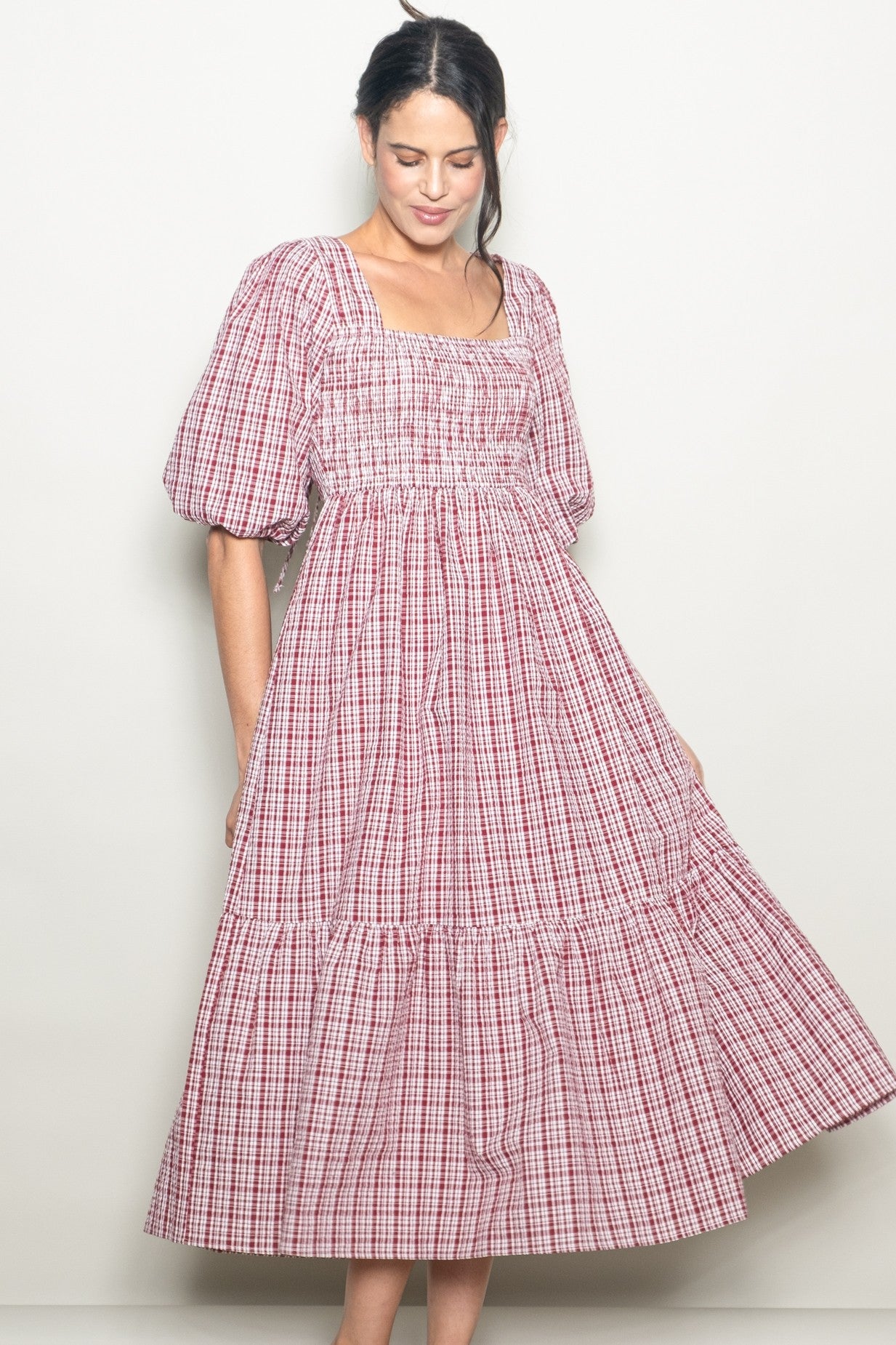 woman wearing a red and white checkered puff sleeve midi dress with a smocked bodice and tiered skirt