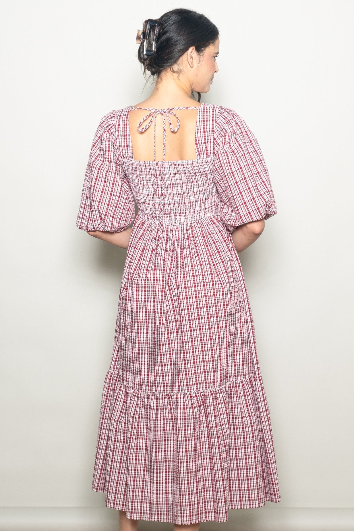 woman wearing a red and white checkered midi dress with puff sleeves and a back tie detail