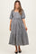 woman wearing a black and white checkered maternity dress with puff sleeves and tiered skirt, showcasing her baby bump