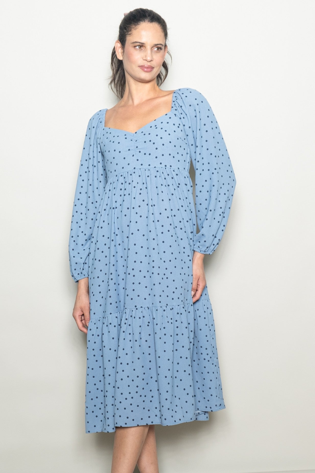 woman wearing a light blue polka dot midi dress with puff sleeves and a tiered skirt