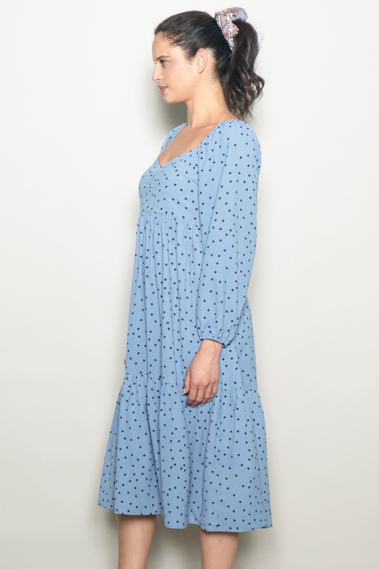woman wearing a light blue polka dot midi dress with long sleeves and a tiered skirt