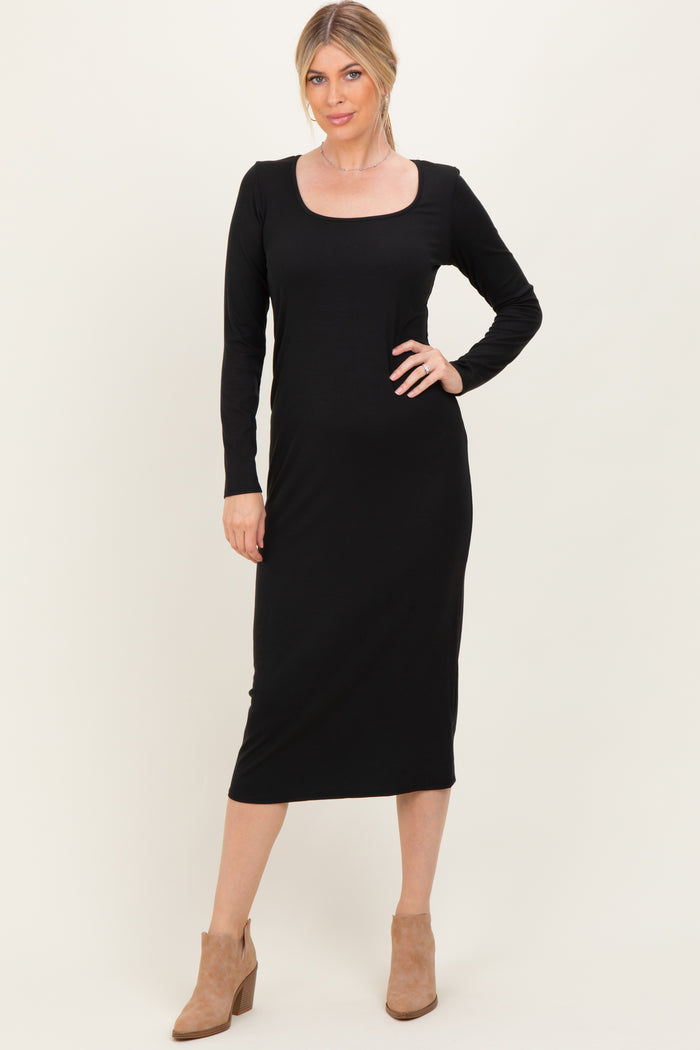 woman wearing a black long sleeve midi dress with a scoop neckline and tan heeled boots