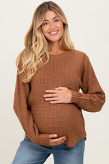 woman wearing a rust ribbed maternity sweater and holding her baby bump