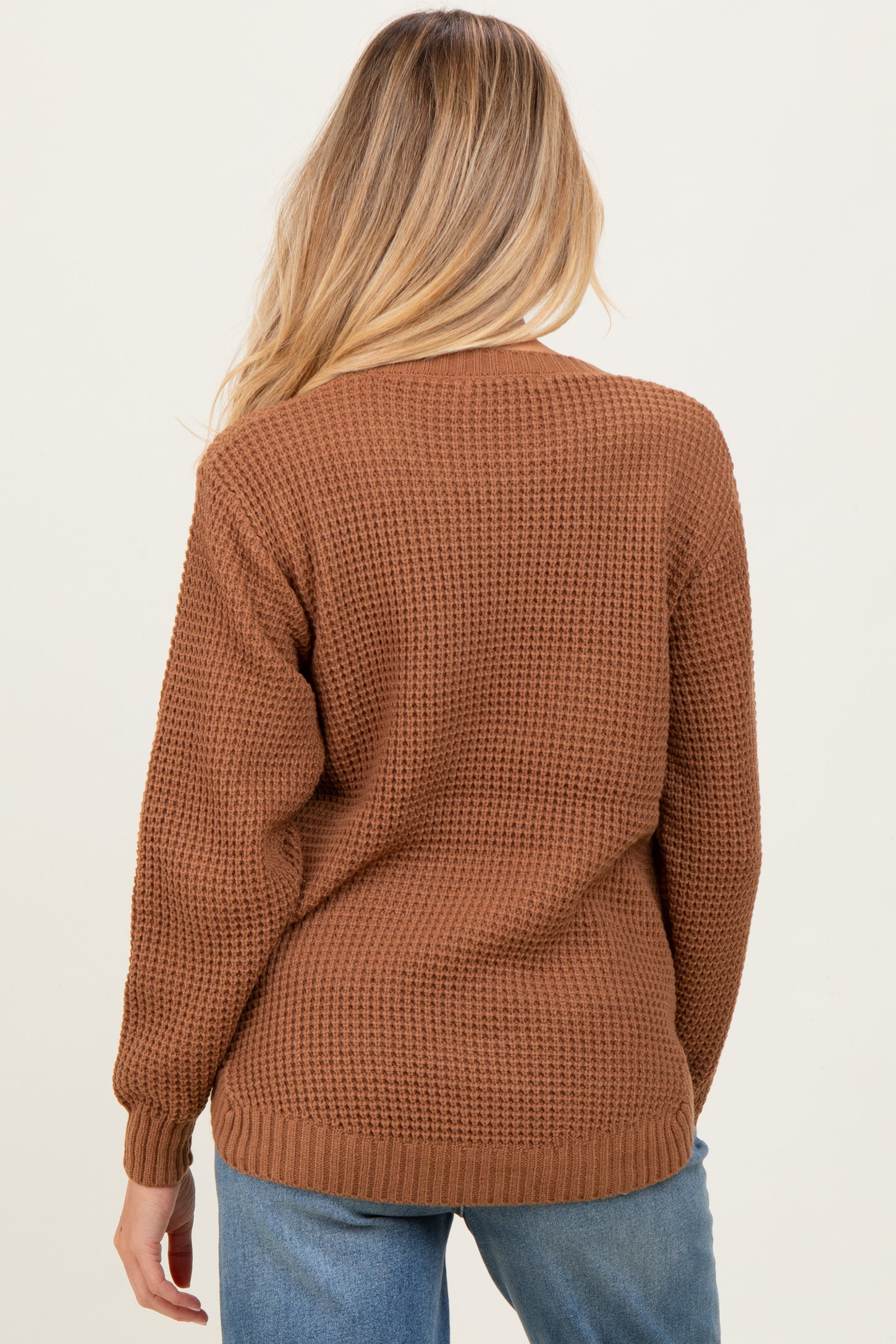 woman wearing a brown knitted maternity cardigan, viewed from the back, showcasing a relaxed fit and long sleeves