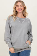woman wearing a gray long sleeve sweatshirt with a v-neck and ribbed details, smiling against a neutral background