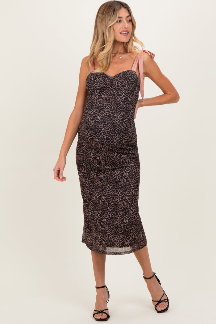 woman wearing a leopard print maternity dress with pink tie straps and a visible baby bump