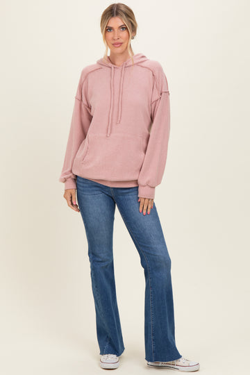 woman wearing a light pink ribbed hoodie with a front pocket and relaxed sleeves, paired with flare jeans