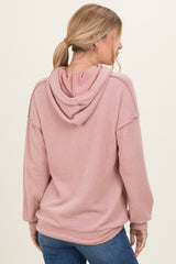 woman wearing a pink ribbed hoodie with a relaxed fit and a hood, viewed from the back