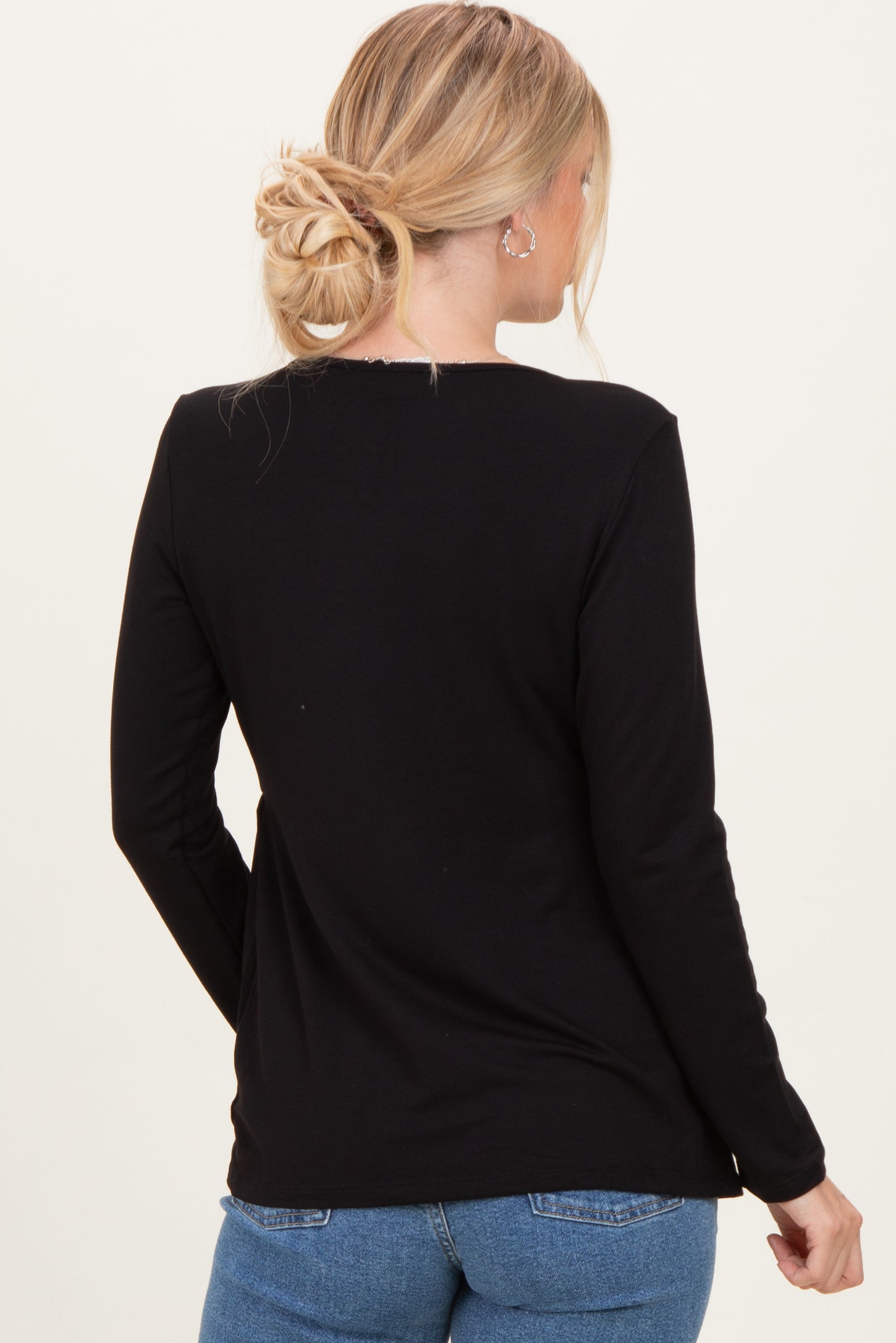 woman wearing a black long sleeve top, seen from the back, paired with light blue jeans