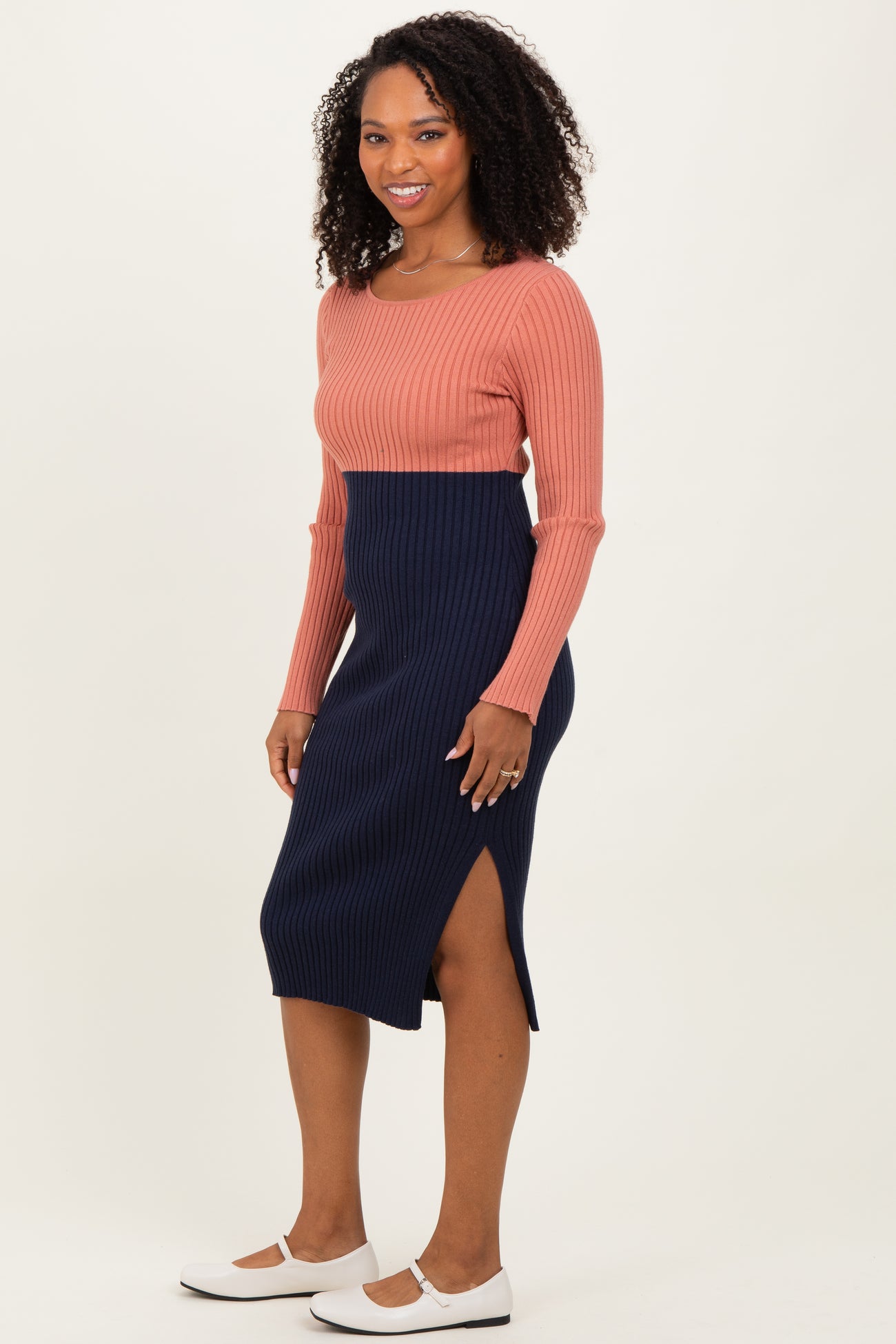 woman wearing a ribbed pink long sleeve top and a navy midi skirt with a side slit