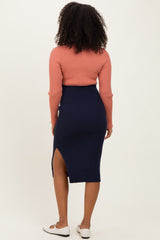 woman wearing a rust-colored ribbed long sleeve top and a navy ribbed midi skirt with a side slit