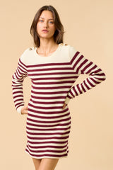 woman wearing a striped maroon and cream sweater dress with button details on shoulders