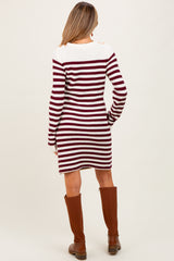woman wearing a maroon and white striped maternity sweater dress, standing with her back to the camera