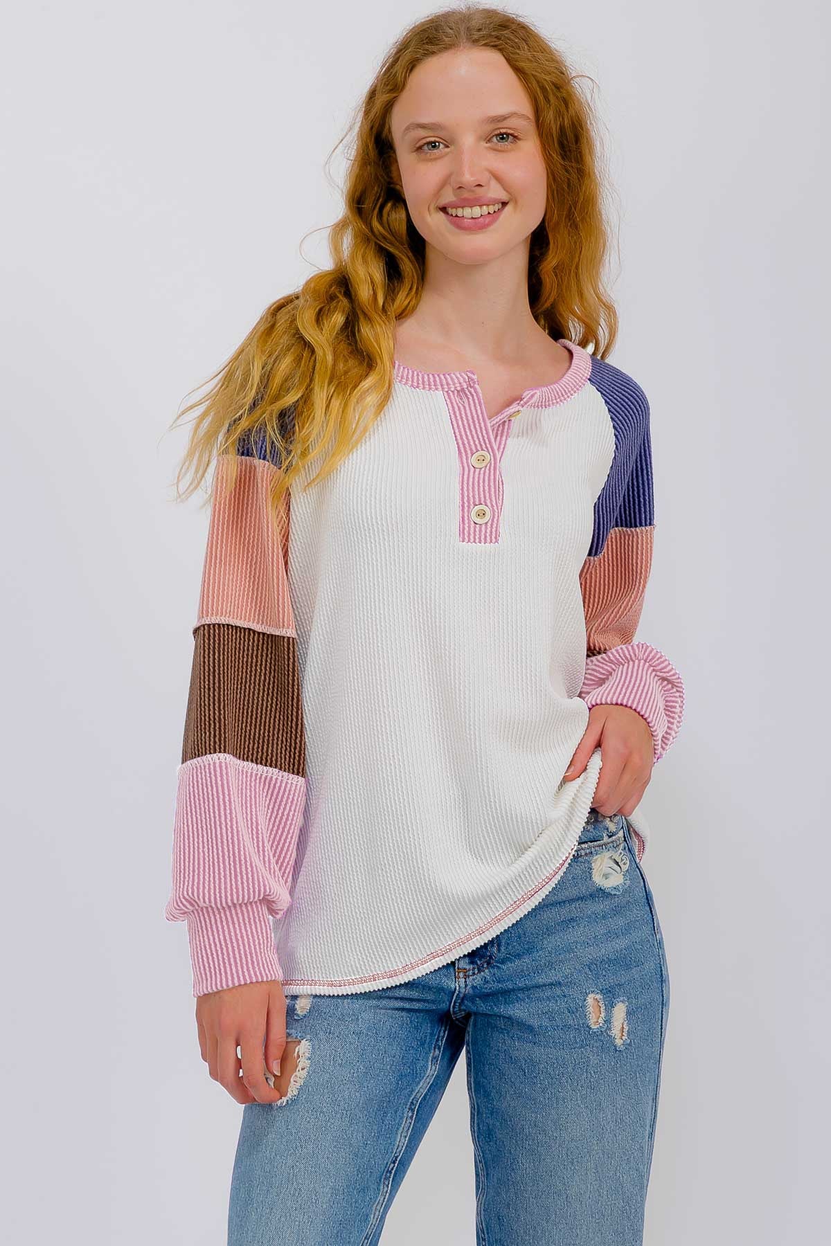 woman wearing a multicolored long sleeve henley top with buttons and a relaxed fit, paired with distressed blue jeans