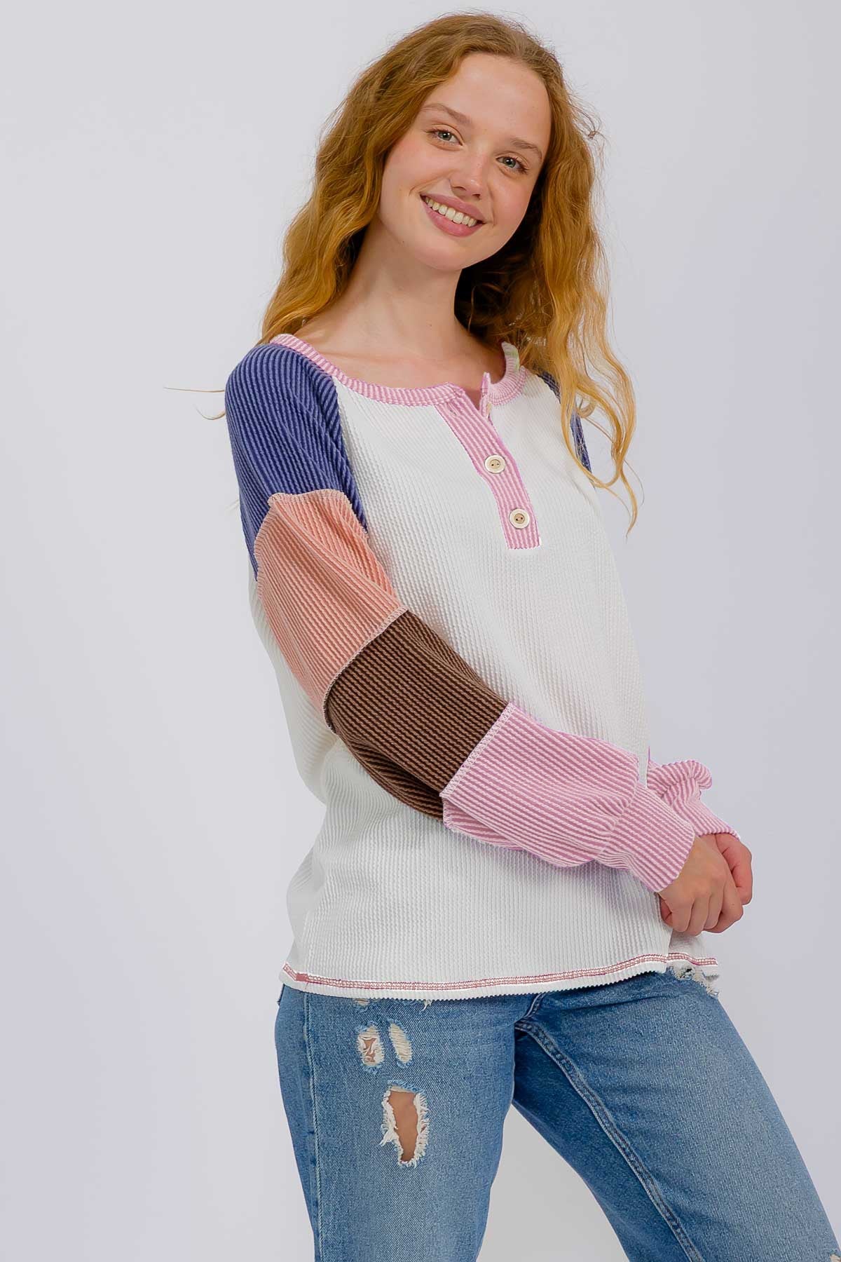 woman wearing a multi-color long sleeve henley top with ribbed sleeves and distressed jeans