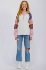 woman wearing a multi-colored long sleeve button-up top with a sporty style and distressed blue jeans