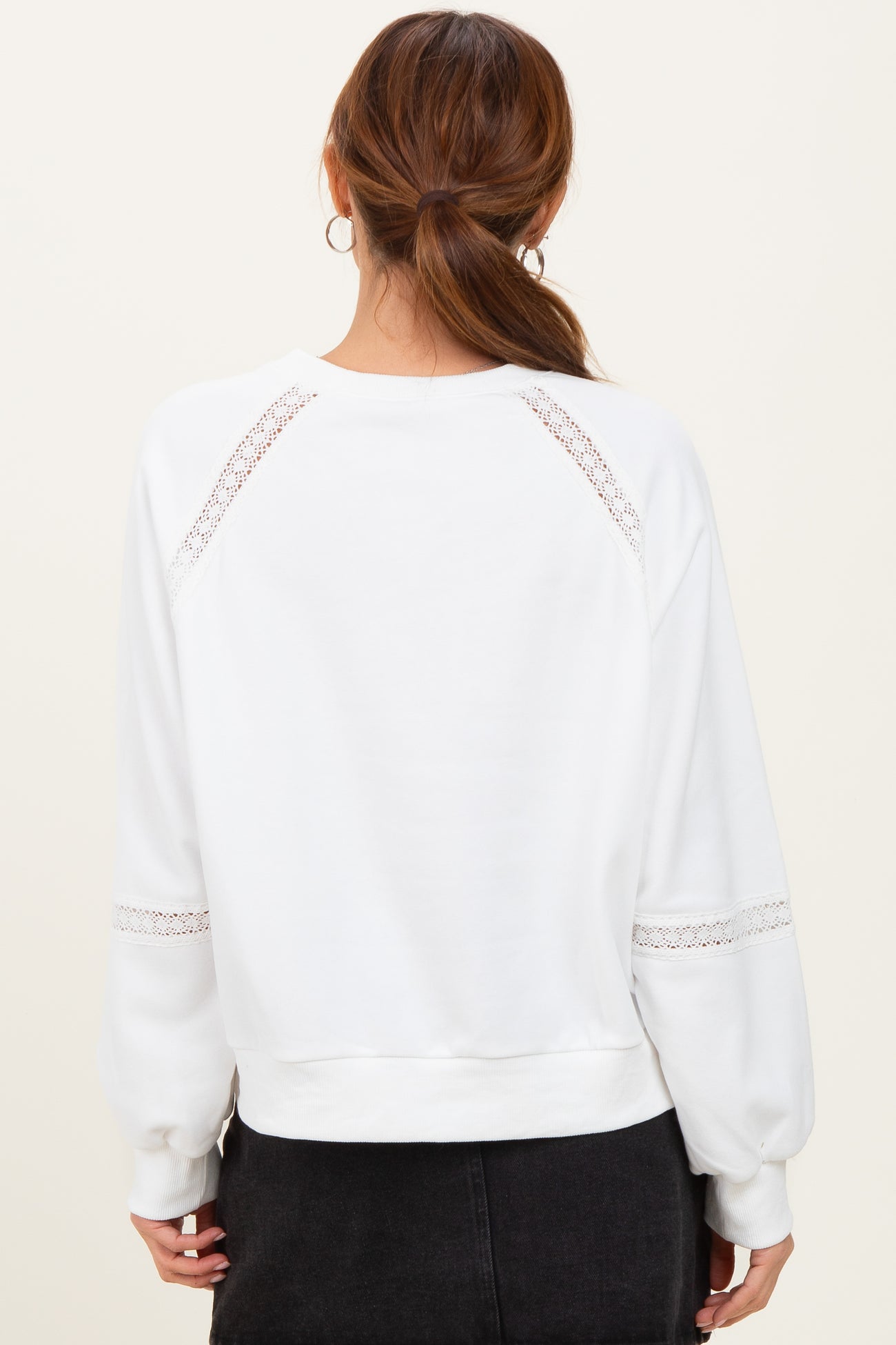 woman wearing a white sweatshirt with lace details on the sleeves and back