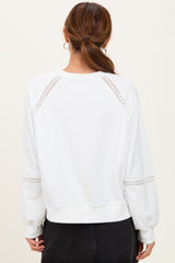 woman wearing a white sweatshirt with lace details on the sleeves and back