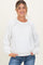 woman wearing a white maternity sweatshirt with lace details and relaxed fit, smiling with hands in pockets