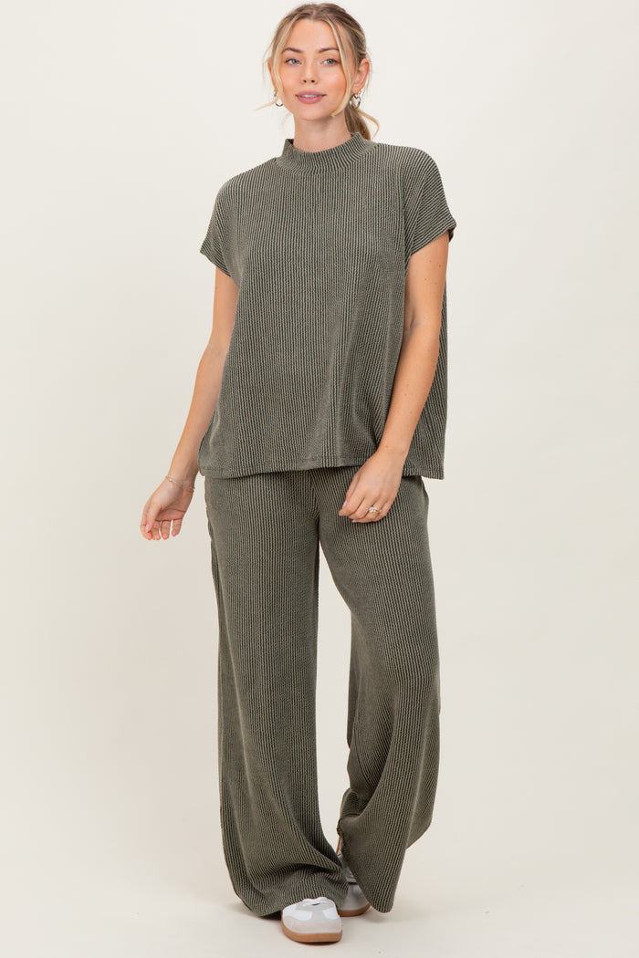 woman wearing a ribbed olive green short sleeve top and matching wide-leg pants, standing against a neutral background