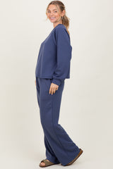 woman wearing a navy blue matching sweatshirt and wide-leg sweatpants outfit, standing sideways with a smile