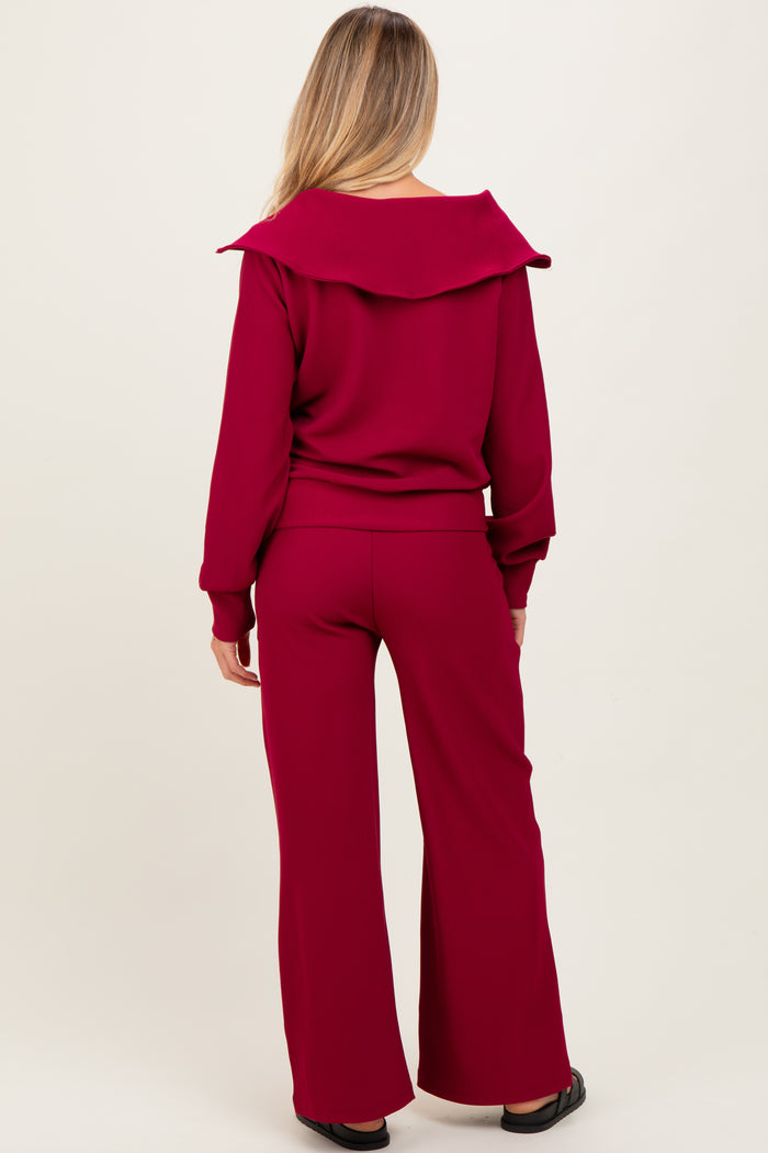 woman wearing a burgundy maternity ribbed top with a wide collar and matching wide-leg pants, showing her back
