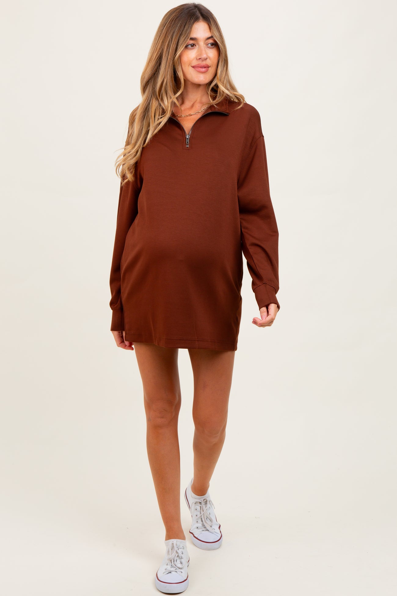 woman wearing a brown maternity zip-up sweatshirt dress with long sleeves and a visible baby bump