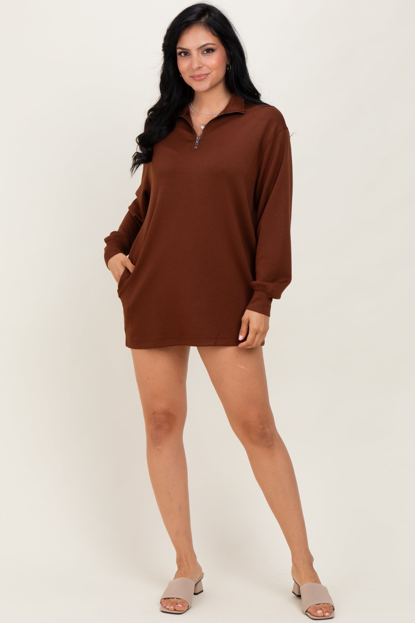 woman wearing a brown long sleeve pullover dress with a zip collar and side pockets