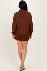woman wearing a brown oversized long sleeve shirt dress, standing with her back to the camera