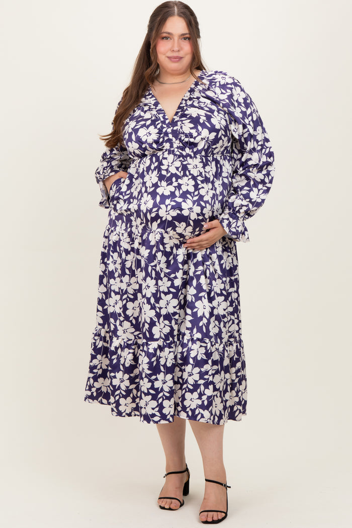 woman wearing a purple floral maternity dress with long sleeves and a tiered skirt, showing her baby bump