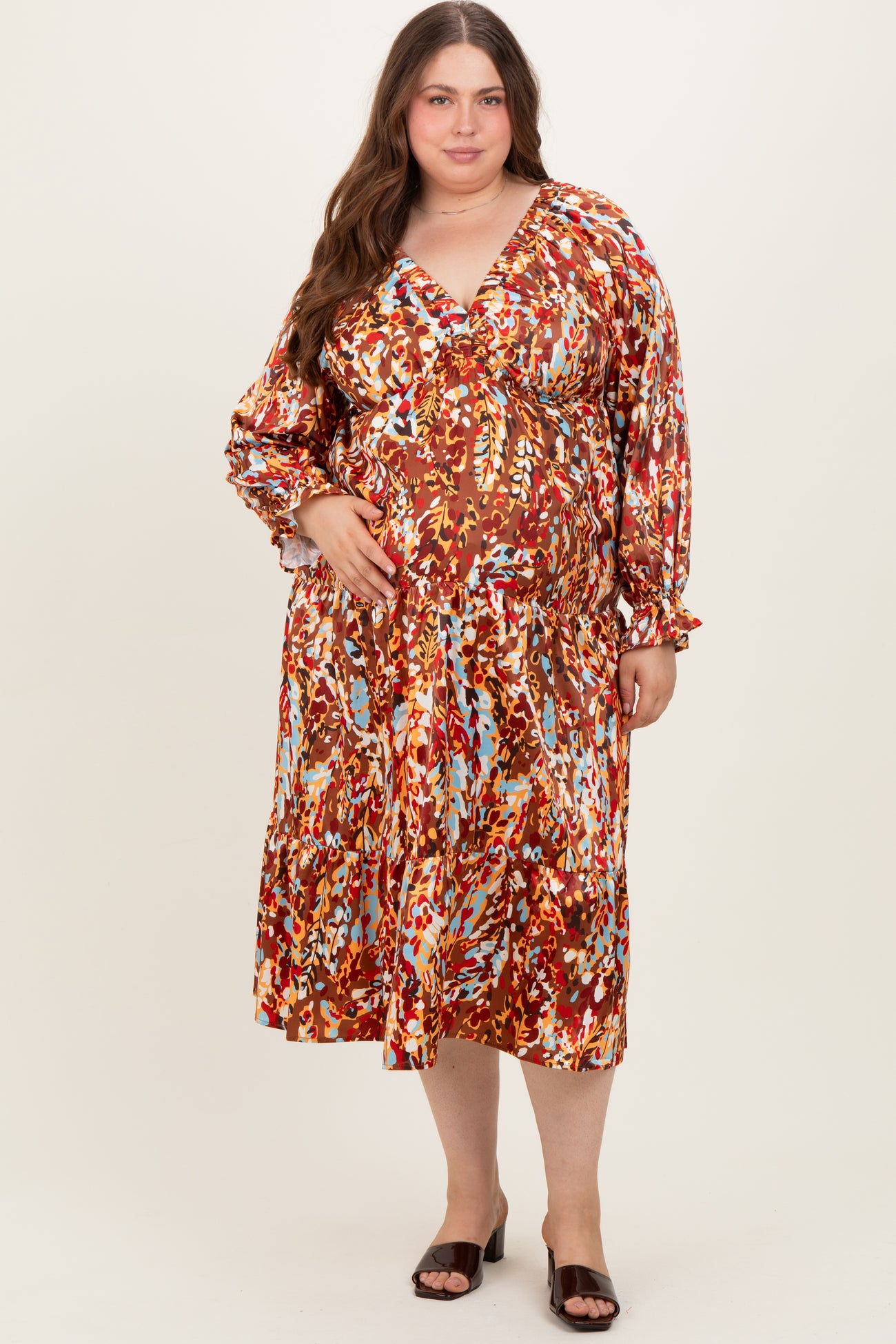 woman wearing a colorful floral print maternity dress with long sleeves and a v-neckline, showcasing her baby bump