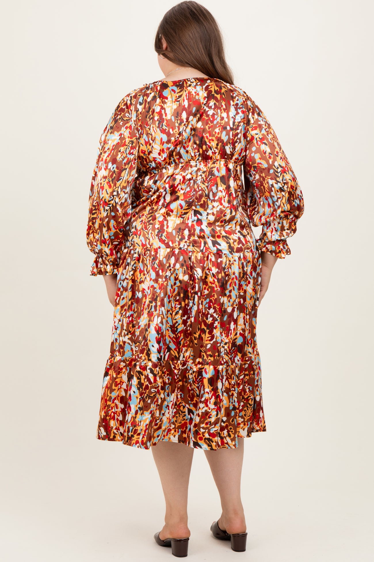 woman wearing a colorful floral maternity plus dress with puff sleeves and ruffle hem, seen from the back