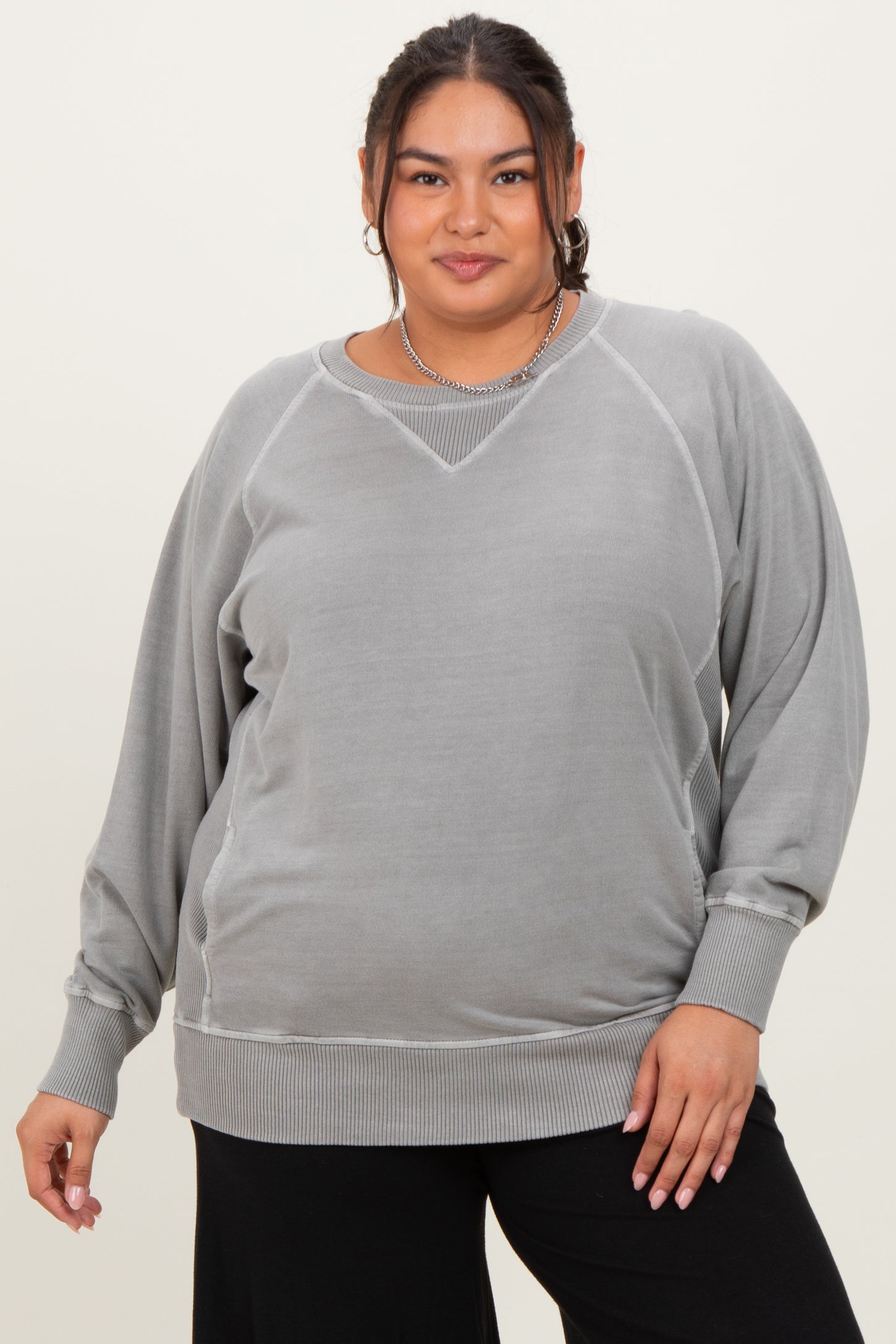 woman wearing a gray plus size sweatshirt with a relaxed fit and ribbed hem, posing with a confident expression