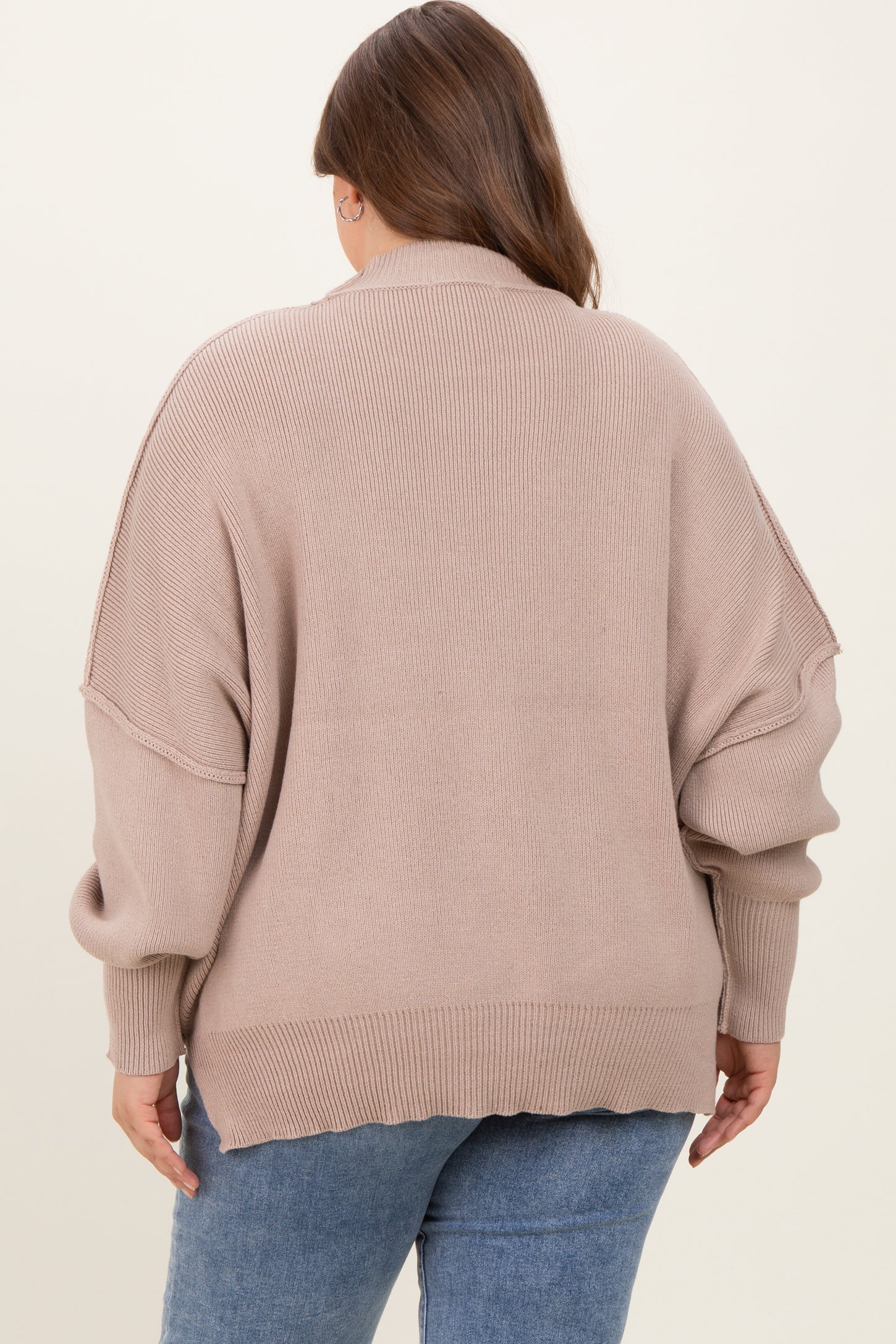 woman wearing a loose-fitting taupe maternity sweater with oversized sleeves and a ribbed texture, seen from the back