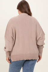 woman wearing a loose-fitting taupe maternity sweater with oversized sleeves and a ribbed texture, seen from the back