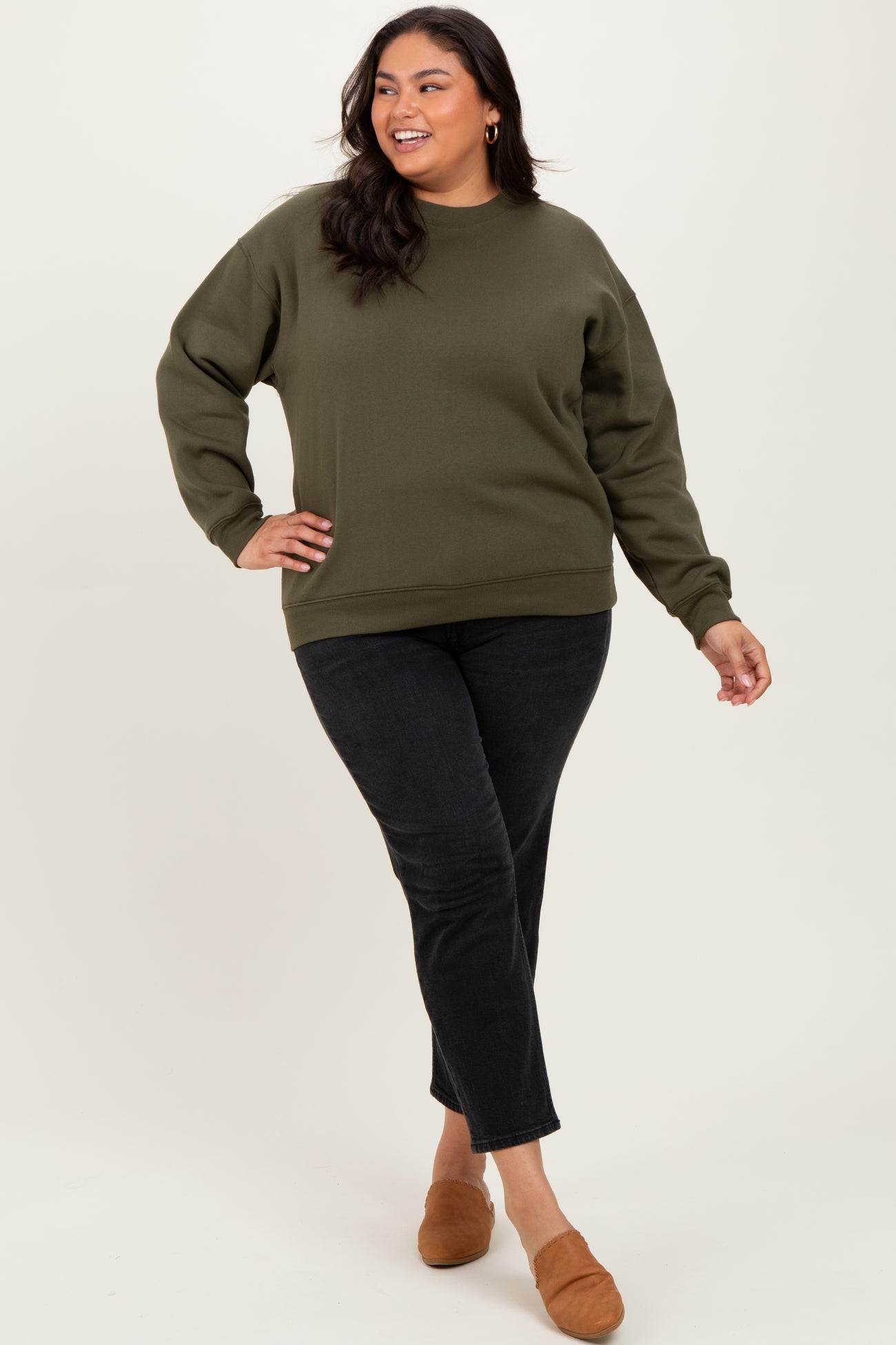 woman wearing a dark green oversized sweatshirt with black jeans and brown slip-on shoes