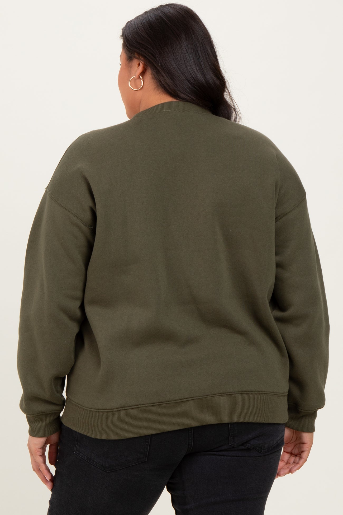 woman wearing an olive green oversized sweatshirt with a relaxed fit and long sleeves, viewed from the back