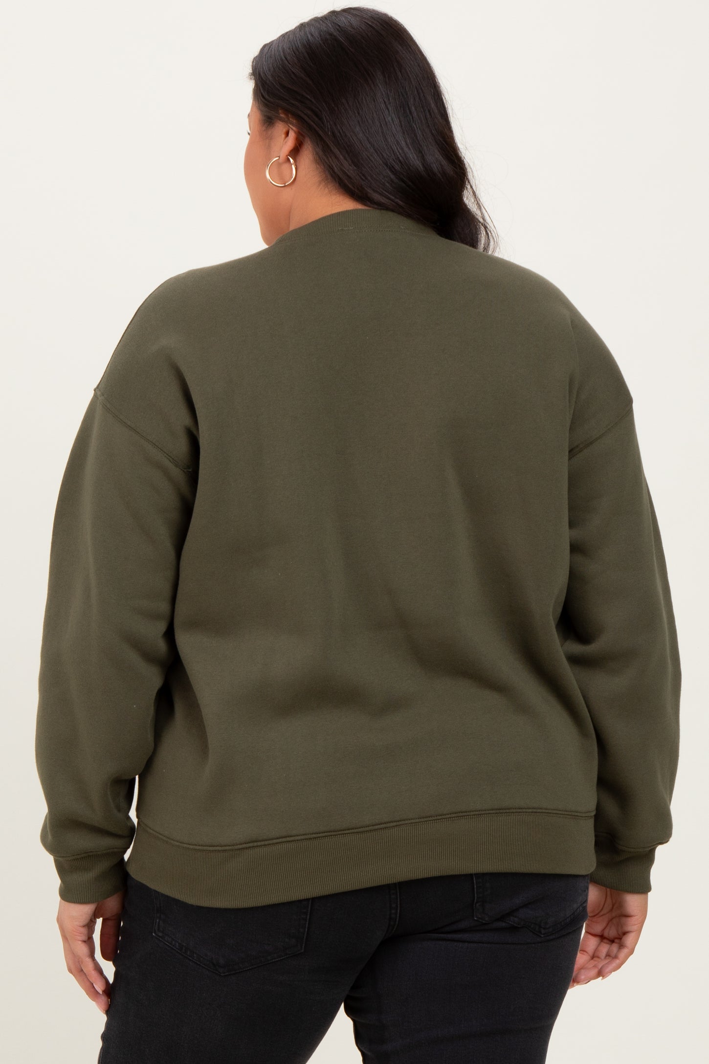 woman wearing an olive green oversized sweatshirt with a relaxed fit and long sleeves, viewed from the back