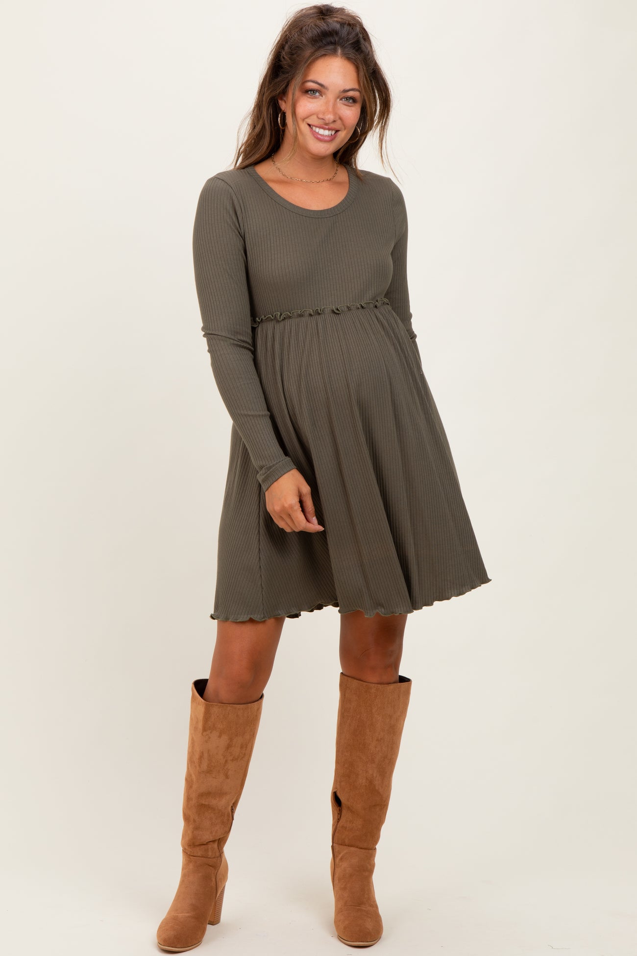 woman wearing a long sleeve olive green ribbed maternity dress with a flared skirt and a baby bump visible