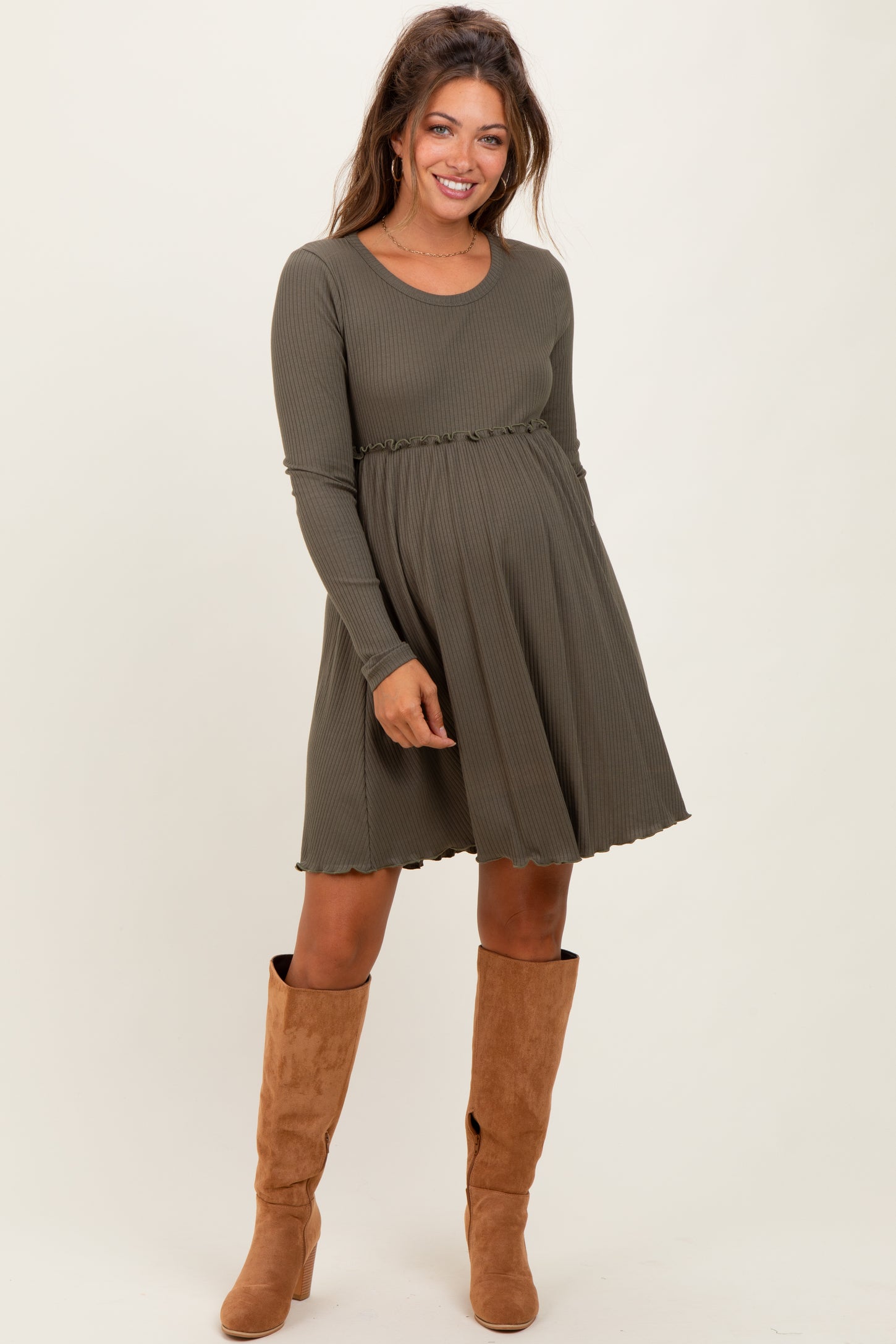 woman wearing a long sleeve olive green ribbed maternity dress with a flared skirt and a baby bump visible