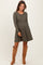 woman wearing a long sleeve olive green ribbed maternity dress with a flared skirt and a baby bump visible