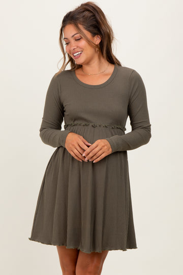 woman wearing a dark green long sleeve maternity dress with a ruffled waistband and a flared skirt