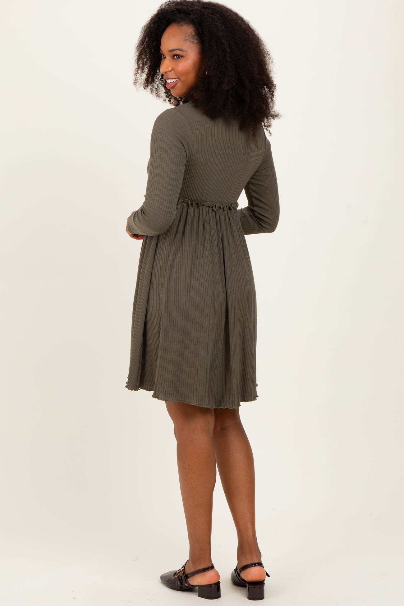 woman wearing an olive green long sleeve dress with a fitted waist and flared skirt, standing sideways