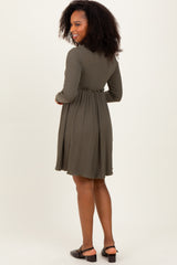woman wearing an olive green long sleeve dress with a fitted waist and flared skirt, standing sideways