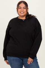 woman wearing a black plus size sweatshirt with loose fit and relaxed sleeves, smiling at the camera