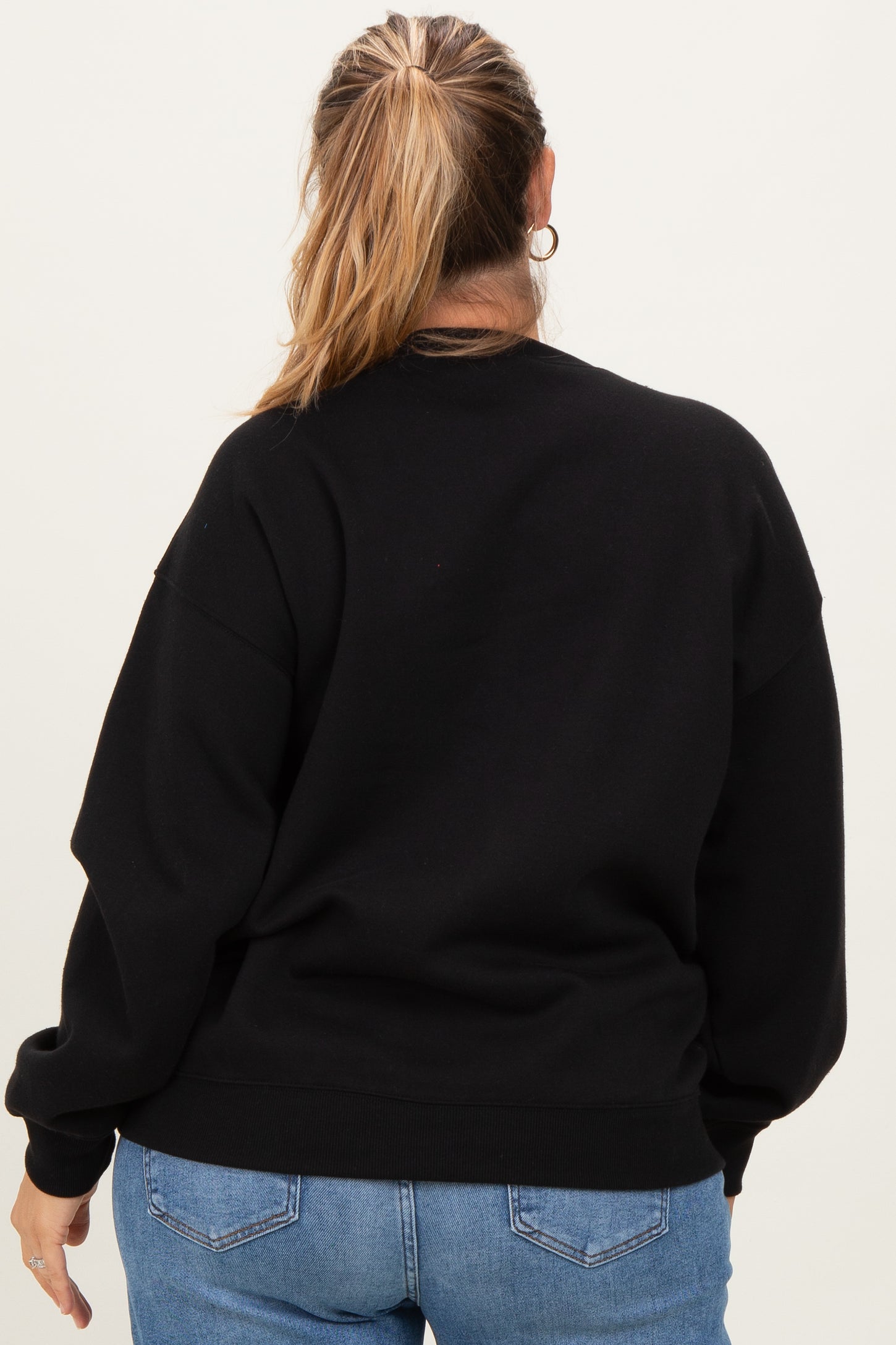 woman wearing a black oversized maternity sweatshirt from the back with long sleeves and relaxed fit