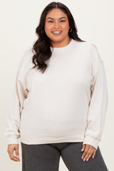woman wearing a light beige plus size sweatshirt with long sleeves and a relaxed fit, paired with dark gray bottoms